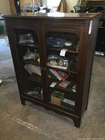 Front view of the vintage wood bookcase with glass doors showing items inside the shelves.