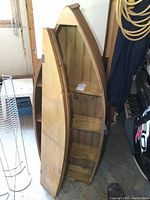 View of both the solid wood canoe-shaped shelf and the separate hinged panel leaning beside it.