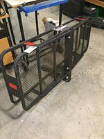 Front-side angle of cargo carrier showing mesh base, metal frame, reflective stickers, and minor wear.