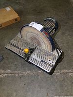Side view of a Mastercraft 12-inch disc sander showing the sanding disc, metal work table with miter gauge, and electric motor housing.