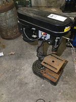 Titan Bench Drill Press full view showing black motor housing, metal base, and rusted adjustable platform.