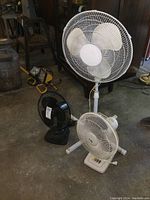 Three fans in total: one white pedestal fan tall about 42 inches, two table fans (one white, one black)