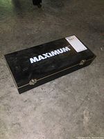 Closed black wooden case with Maximum brand logo on top.