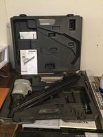 Porter Cable framing nailer and accessories in open plastic case on table.