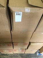 Closed cardboard cases stacked on a pallet, showing four large boxes containing the sanitizer bottles.