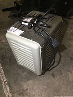 Heater showing side vented panel and attached power cord coiled on top.