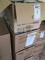 Photo of stacked cardboard cases containing nitrile gloves, with partial case open showing boxes inside.