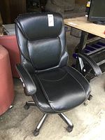 Side angle of black leather office chair showing cushioned seat, padded armrest, and adjustable height.