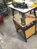 Side view of router table on removable stand with lower shelf and pegboard panels
