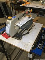 Full view of the Ryobi 16-inch bench top scroll saw on a white table, showing the entire saw body and work surface.