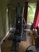 Full view of the Apex universal weight machine from the front showing lat pulldown bar and padded seat.