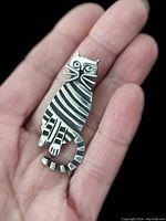 Silver cat brooch shown on hand to depict scale and design.