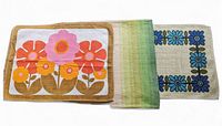Photo showing three placemats with flower print, gradient stripes, and blue flower border pattern laid side by side.