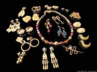 Large assortment of vintage costume jewelry laid out including earrings, beaded necklace, and brooches in gold-tone and colorful beads.