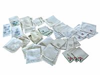 Large assortment of vintage embroidered linen and cotton handkerchiefs and napkins laid out showing variety of sizes and embroidery styles.