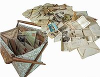 Large assortment of aged handwritten letters, postcards, photos, and clippings spread out with the knitting basket visible.