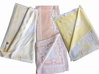 Folded view of three pastel tablecloths showing yellow, pink, and another light colored one with visible fabric patterns.