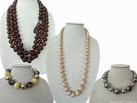 Photo of three necklaces displayed on necklace stands showing different colors and bead sizes.