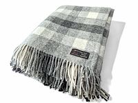 Folded grey and cream check wool throw blanket showing fringed edges and an original sewn tag indicating 100% pure new wool and made in Lithuania.