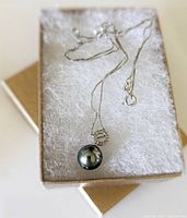 Necklace placed in jewelry box with white cushioning showing pendant and chain detail.