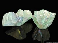 Two vintage iridescent handkerchief art glass bowls on black reflective surface, showing shape and color.