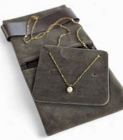 Necklace and pendant displayed on grey velvet pouch