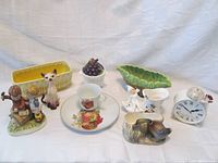 Overview of all porcelain items including clock bank, planters, figurines, and teacup set