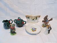 Overview photo showing all six items in the lot including three figurines (Robin bird, Bride & Groom, Leprechaun), white roses planter, bon bon dish, and creamer with sugar bowl.