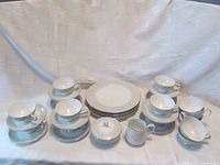 Full set displayed showing all plates, teacups with saucers, additional teacups, creamer and covered sugar bowl
