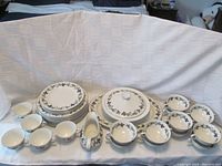 Complete set of Royal Doulton dinnerware including plates, bowls, cups, covered vegetable dish, and serving platter arranged on a white cloth background.