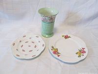 Three Shelley Fine Bone China pieces on white fabric background: a green footed vase with floral band, a salad plate with scattered flowers, and a dessert/pie plate with floral bouquets on rim.
