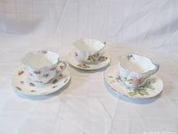 Three Shelley fine bone china teacup and saucer sets shown together displaying their floral patterns and scalloped rim shapes.