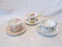 Three Shelley fine bone china teacup and saucer sets with distinct floral patterns in pink, yellow/pink, and blue/green.