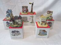 Photo showing all five Liberty Falls miniatures each on their original box. Items include Clark Mansion, Ross Brothers Clothier, Dr. Steven's Home & Office, Old Home Restaurant, and Aunt Alice's Quilt Shop with a windmill piece.