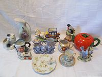 Lot overview of thirteen vintage Japanese porcelain pieces arranged on white background, showing details of various mugs, planters, teapot, and other ceramic items.