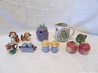 Overview of all 8 porcelain kitchenware and decorative collectible items including creamers, jam pot, pitcher, and salt & pepper sets placed on white background