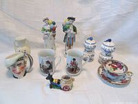 Collection of porcelain and ceramic items including figurines, mugs, salt and pepper shakers, and teacup with saucer.