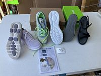 Photo showing the two pairs of shoes side by side; Skechers runners and black leather sandals, both with soles visible