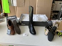 All three footwear items displayed on a table: brown slip-on shoes, black boots, and black sandals with heel.