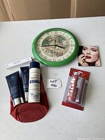 Overview photo showing all items on white table including the green Christmas clock, cosmetics, wrap cutter, and carry bag.