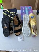 Pair of black leather sandals with dual straps and textured rubber sole. Yellow leather runners with lace-up and white sole placed next to them, showing condition and soles.