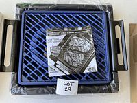 Photo of blue electric grill with black handles and a user manual on top showing steak on the grill surface, illustrating the product’s features like non-stick triple-layer coating with titanium and diamond.