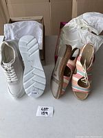Photo showing both pairs of shoes: white sneakers on the left and striped sandals on the right inside their boxes with tissue paper.