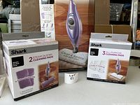 Photo of Shark Steam Pocket Mop in original box with two boxes of replacement cleaning pads in front, showing lot contents.