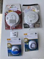 Lot of two Kidde smoke alarms and two GE basic light timers, still in packaged condition, shown on concrete floor