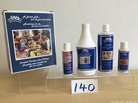 Photo of four different sized bottles of UV furniture care products arranged next to their original box with label 140 in front.