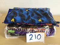 Stack of around 10 different folded Halloween themed fabric pieces with bat and moon patterns, wrapped in plastic packaging.