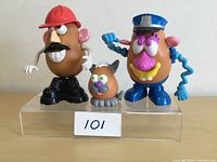 Front view of three Mr. Potato Head figures displayed on clear acrylic stand, showing detailed facial features and accessories