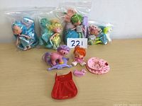 Full lot of five dolls and accessories, some sealed in plastic bags, laid out on table with number card 221