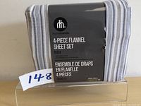 Front view of the packaged 4-piece flannel sheet set showing the striped grey and white pattern with brand and product details.